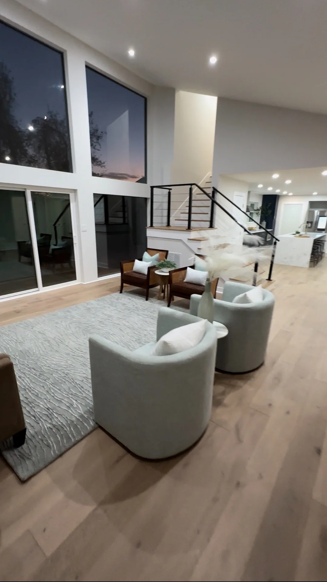 Finished great room at dusk with floor-to-ceiling windows
